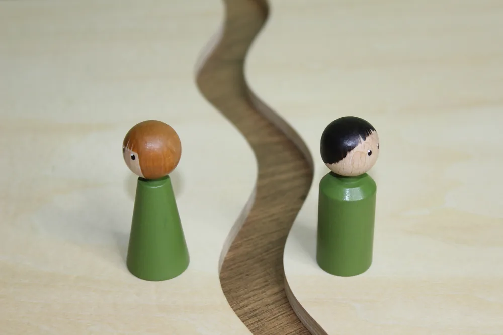 Zwei Holzfiguren an einem geschwungenen Weg